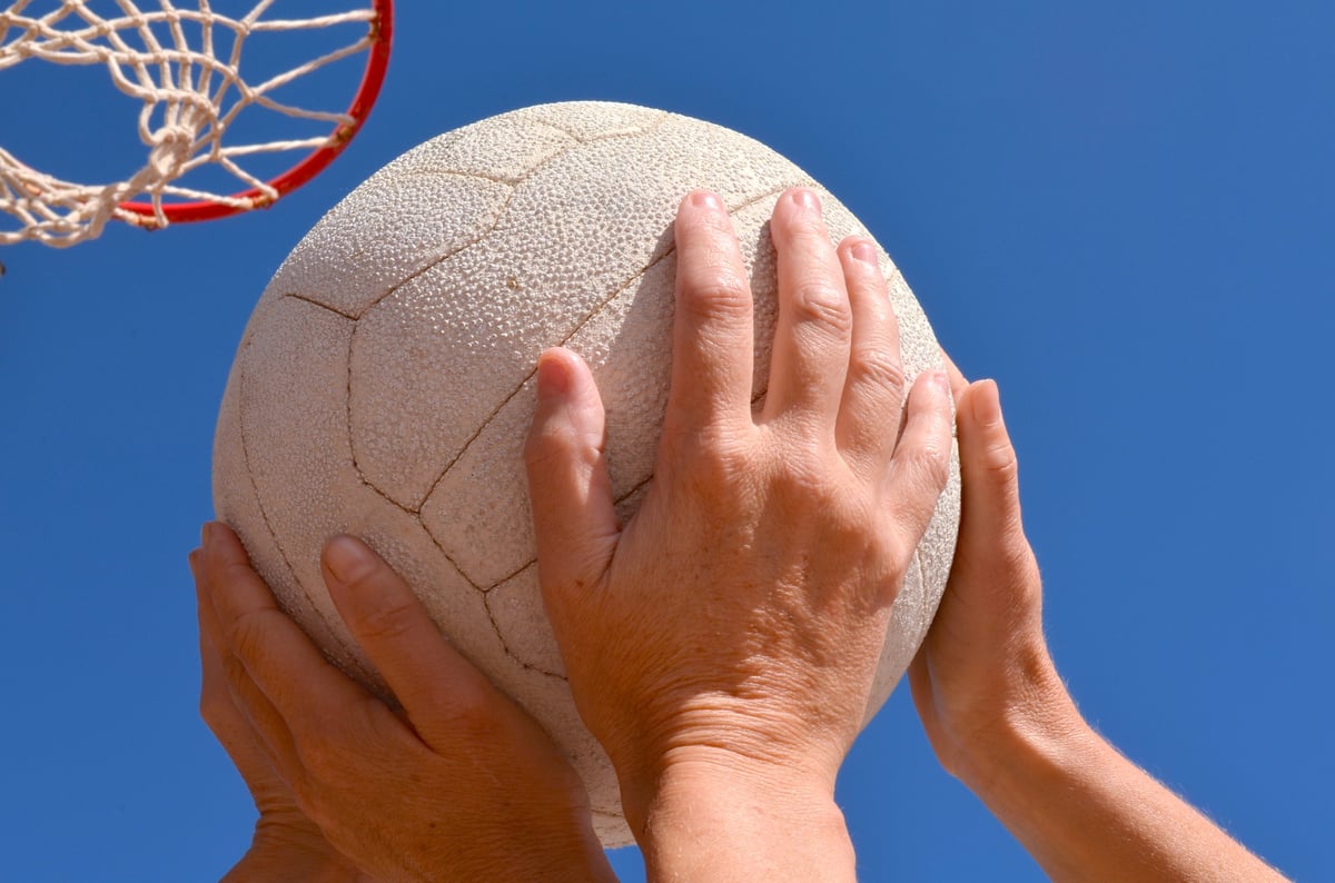 Two netball players competing for the ball under a netball ring