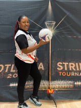 Woman holding a volleyball in front of a Portland Strikes Tournament banner with a basketball hoop design backdrop