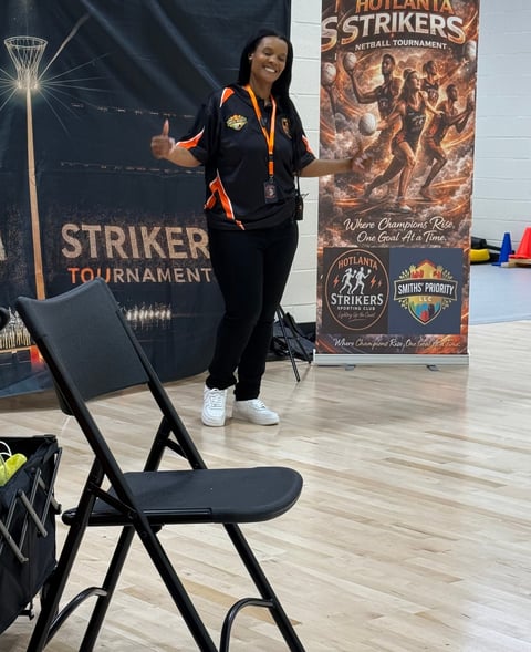 Woman posing at Outlanta Striker Tournament indoor volleyball event with promotional banners in background