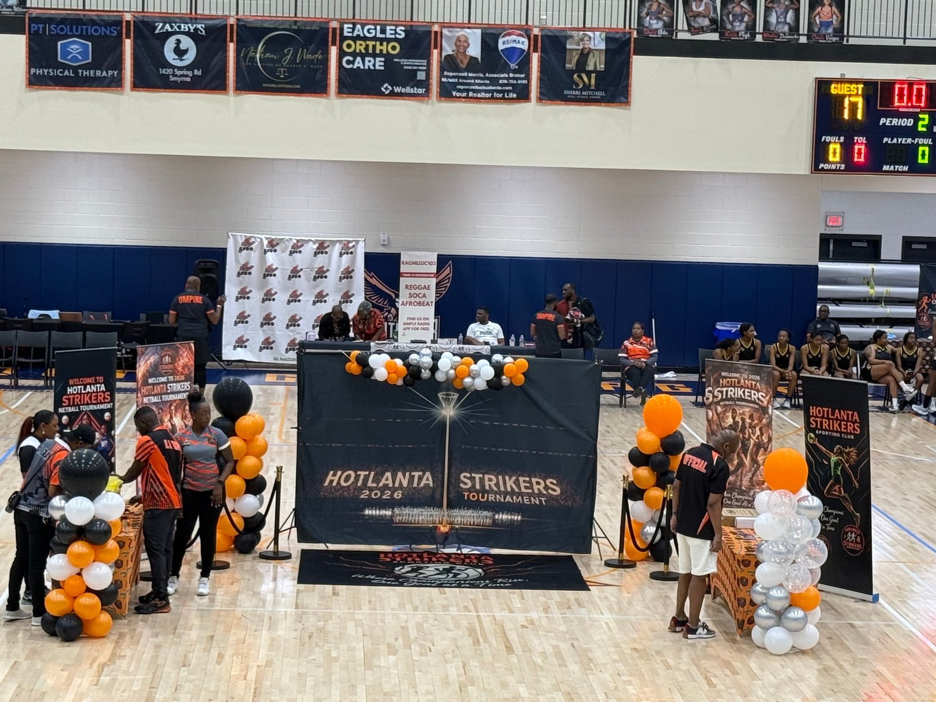 Atlanta Strikers tournament setup with orange and white balloons, branded signage, and teams gathered in a gymnasium